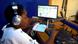Person with headphones sitting at a computer at Nyanthepa Community Radio in Malawi.