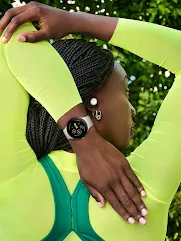 A person wearing neon yellow clothing, Pixel Buds and a Pixel Watch stretches their arm behind their back.