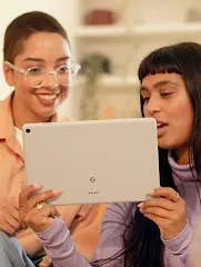 Two people smile while looking at a tablet.