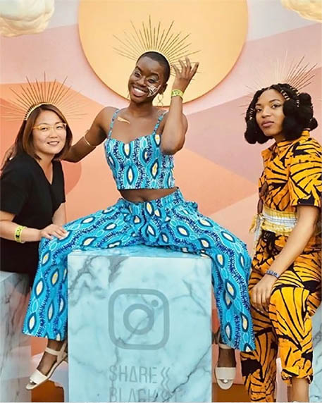 three friends in bright patterned clothes posing with crowns