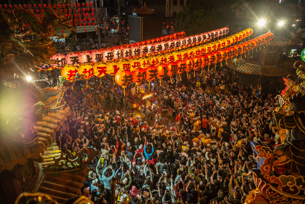 夜幕降临,在明亮的灯光和五颜六色的灯笼下,一尊雕像被抬上銮驾,来到一座挤满了人的寺庙。