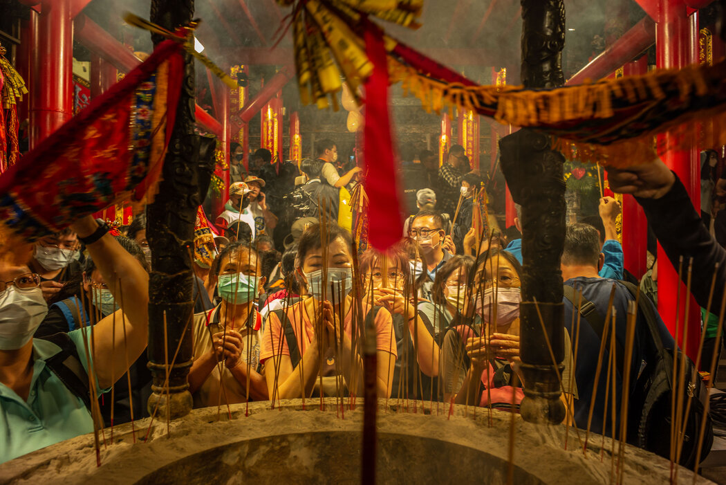 妈祖的追随者在一座寺庙的妈祖像前鞠躬并点燃香火。