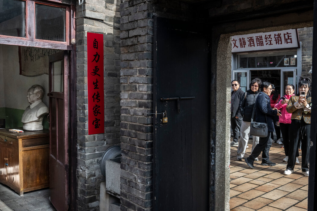 陳家舊居外的遊客,門前陳列著毛主席的半身像。門邊的條幅寫著「自力更生傳家寶」。