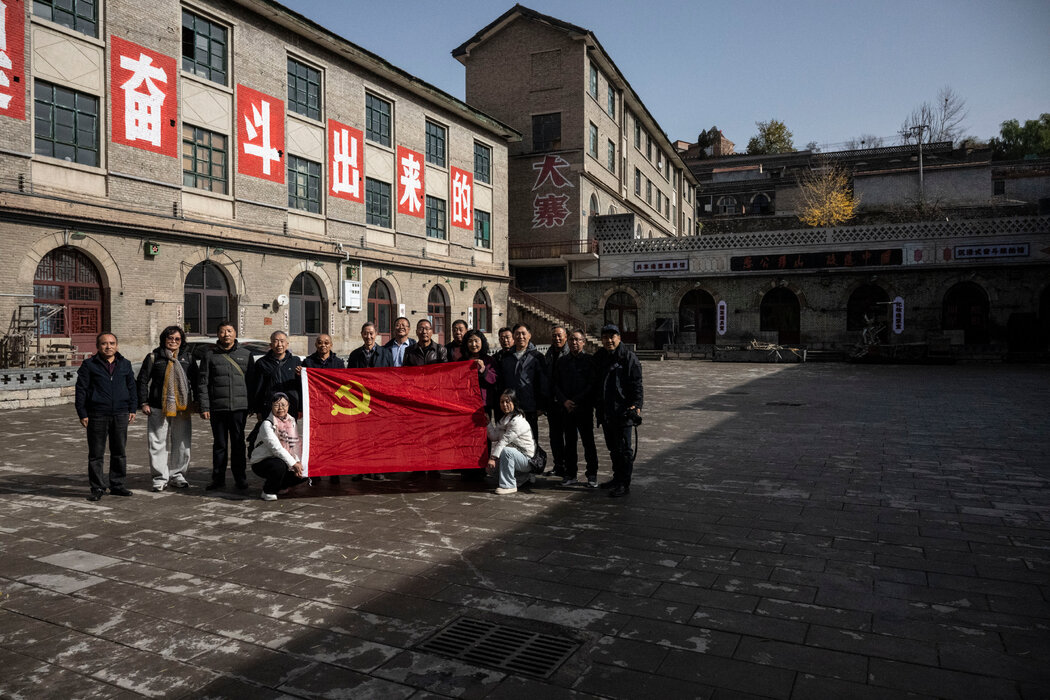 大寨人民公社舊址的遊客手持黨旗合影。他們身後是習近平呼籲奮鬥精神的口號。